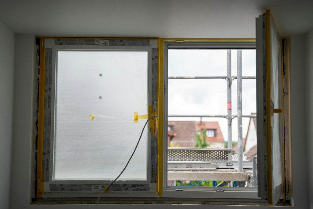 Frisch eingebautes Fenster mit Schutzfolie, draußen das Baugerüst